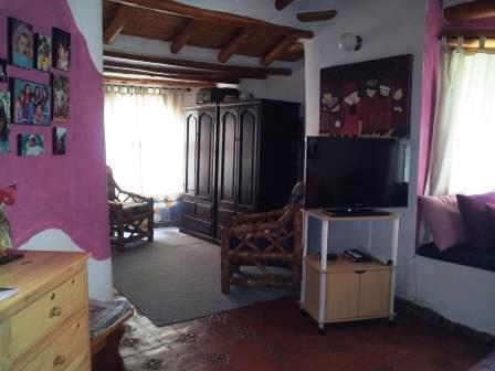 Sala con sofá, televisor y puerta de entrada.